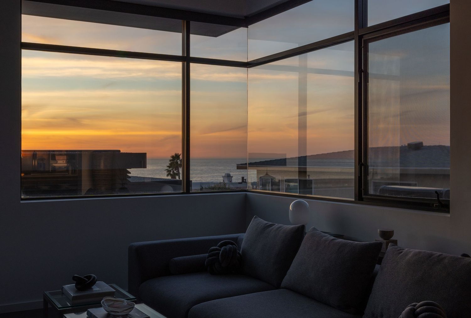 Panoramic windows reveal dramatic sunset view over urban skyline.