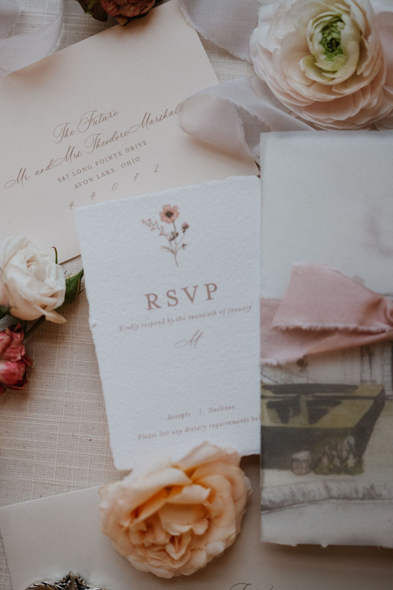 Elegant wedding RSVP card with blush roses and calligraphy details on white linen.