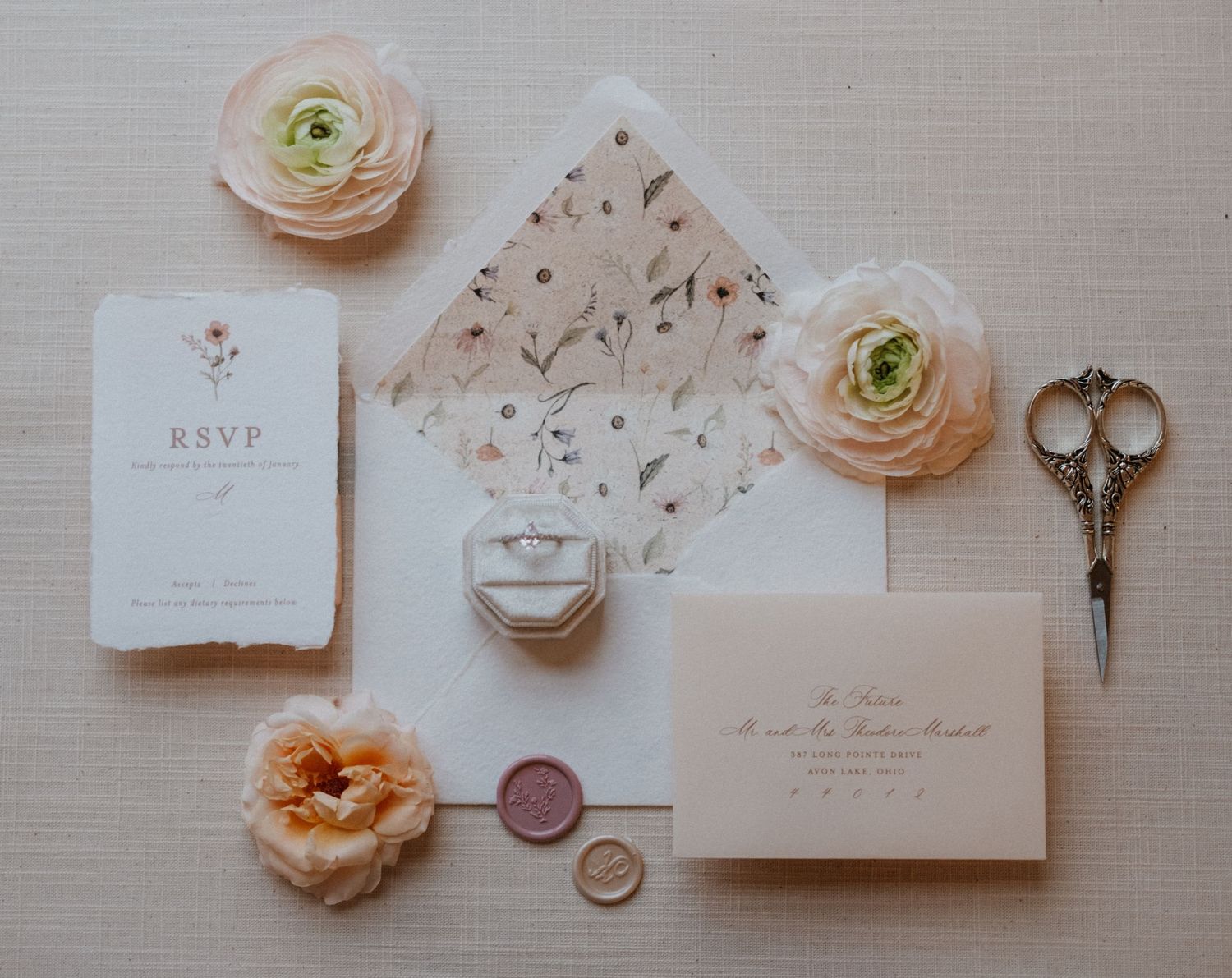 Wedding invitation suite with antique key, floral envelope liner, and peachy ranunculus blooms.