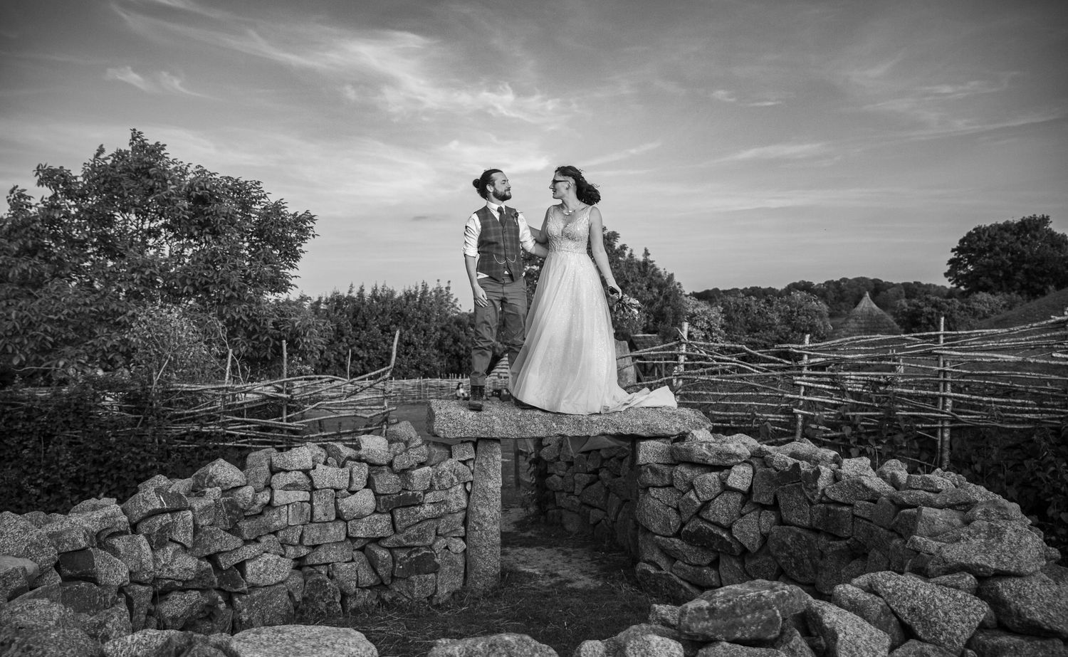 Dramatic black and white landscape with stone walls under cloudy skies.