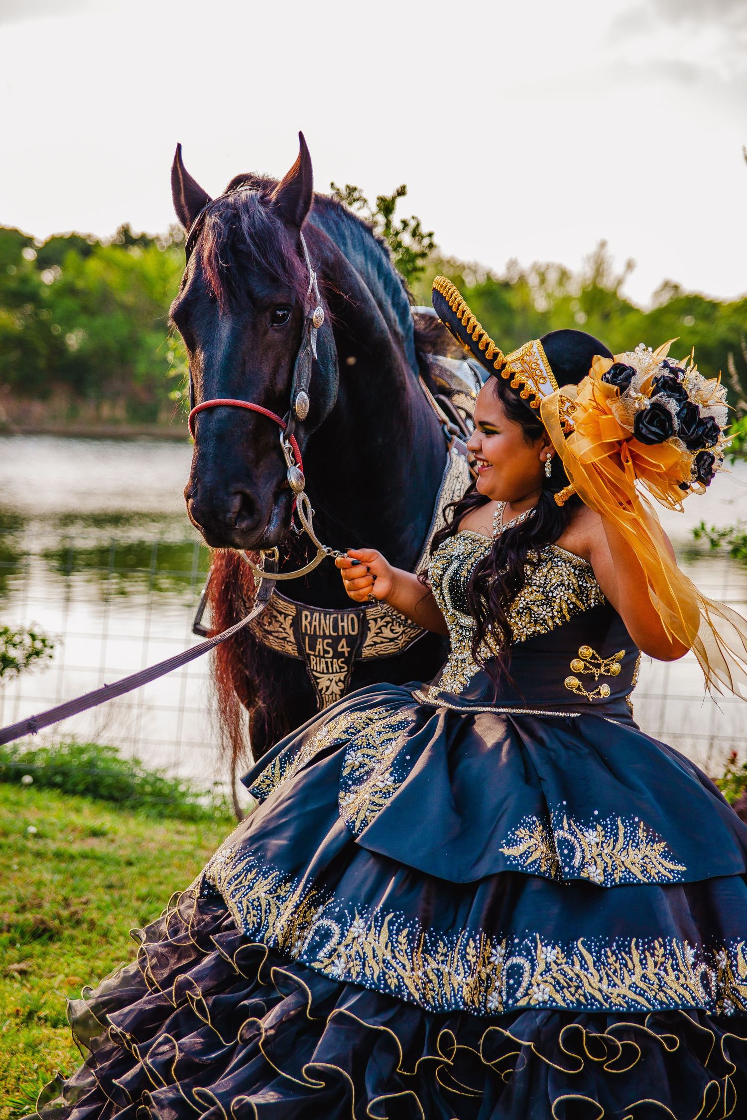 Dramatic navy blue and gold embellished dress photographed with black horse by waterfront.