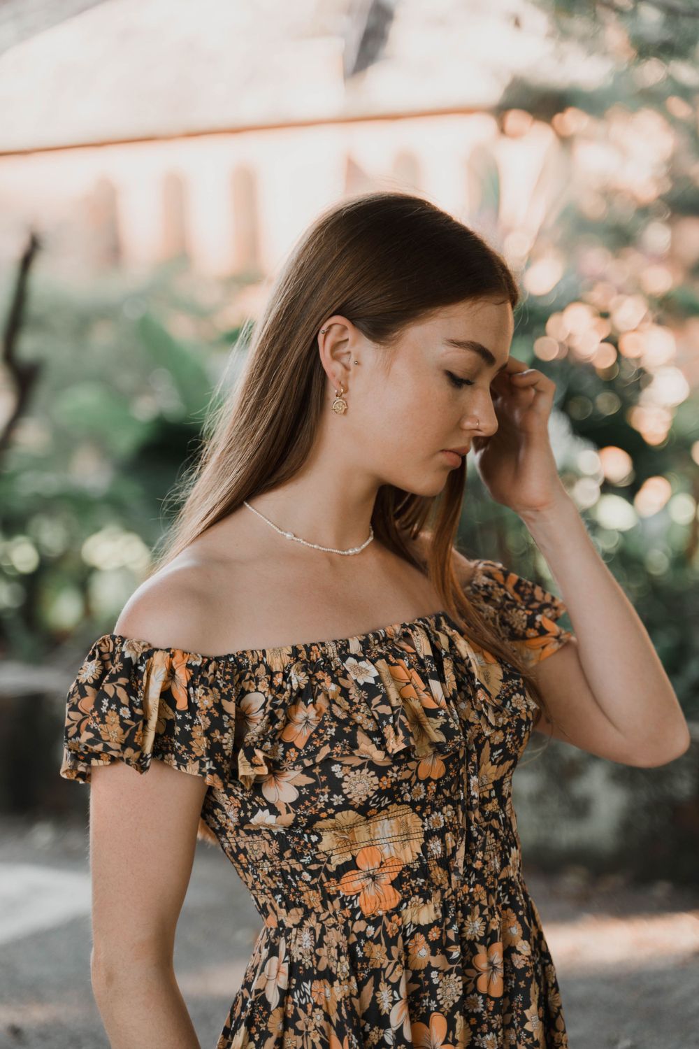 Off-shoulder floral dress with delicate necklace photographed in soft natural lighting.