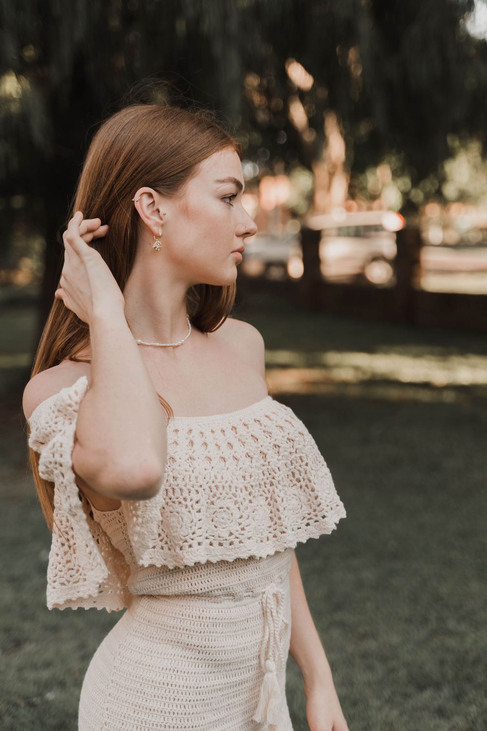 Side profile shot of off-shoulder white crochet dress in golden hour lighting.