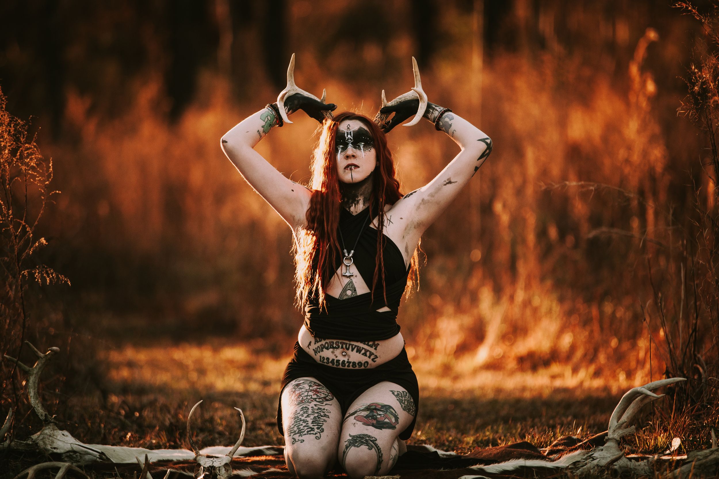 A gothic themed photoshoot in a forest with orange backlighting.