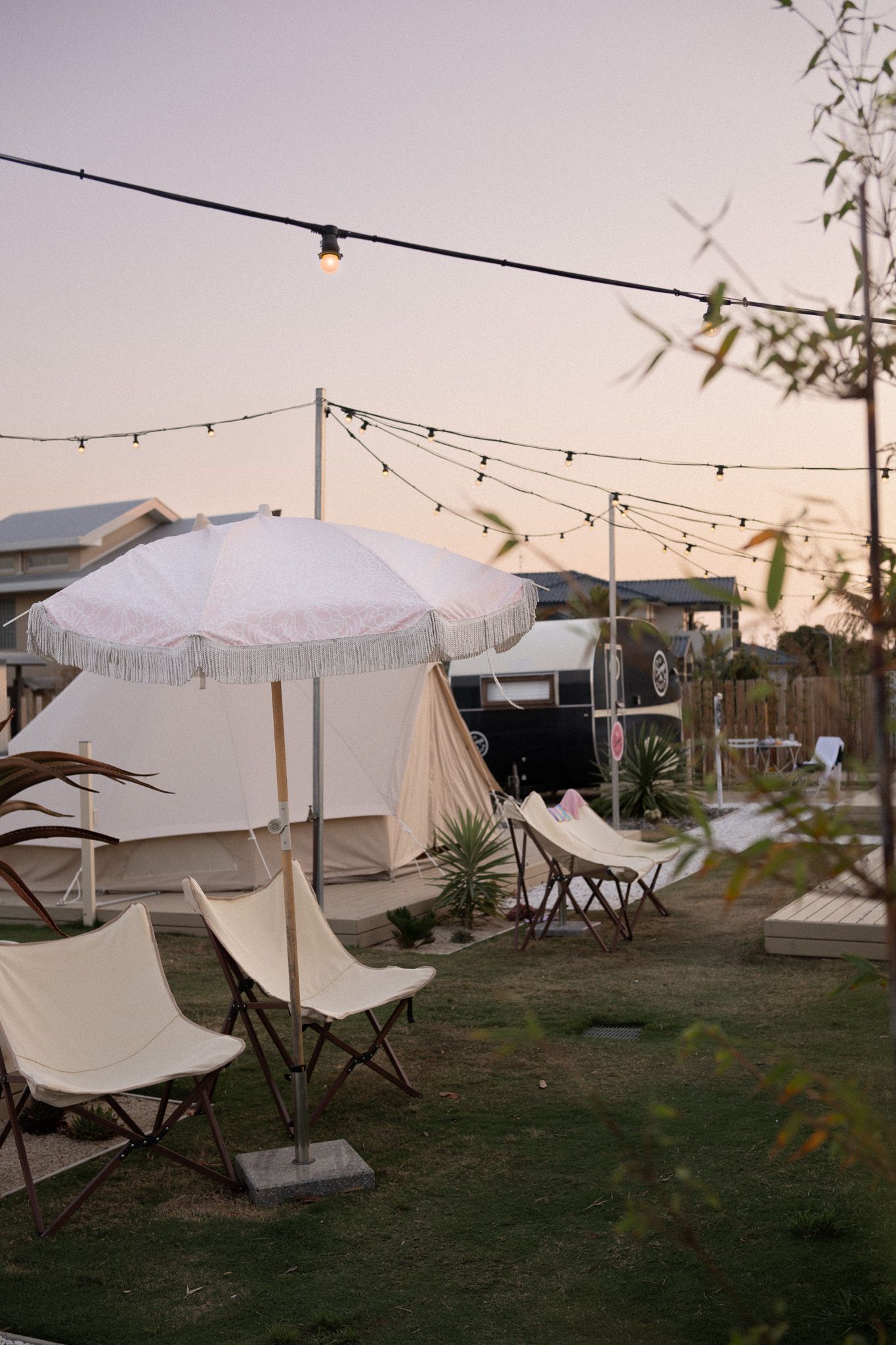Camp Jordans beachy vibe fringed umbrellas and chairs in front of boho tents.