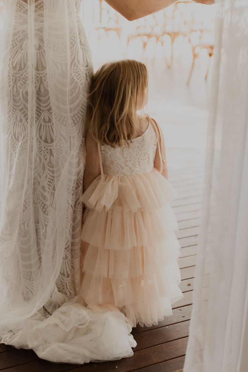 A little girl stands by her mothers side looking out into the distance