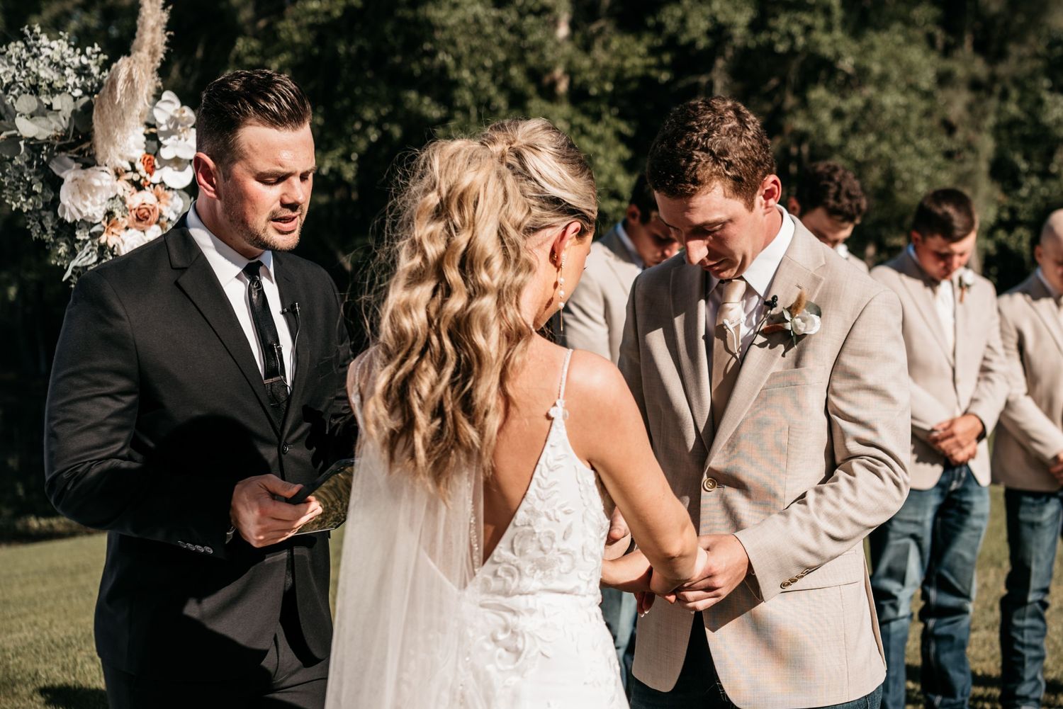 An outdoor wedding ceremony taking place on a sunny day with elegant decor and floral arrangements.
