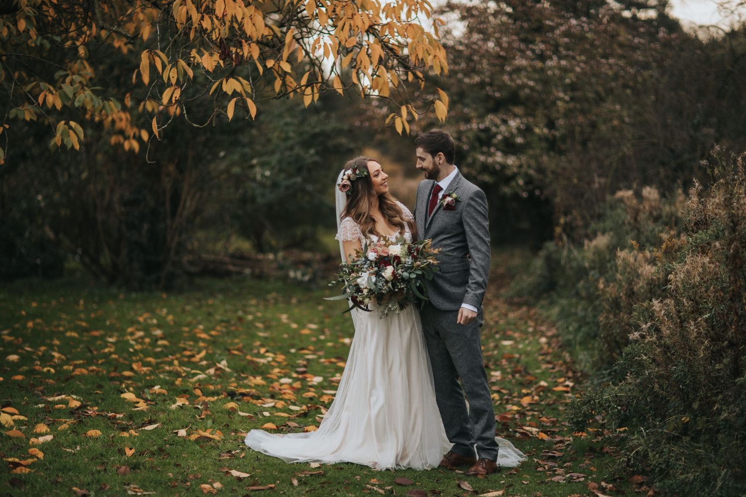 Autumn wedding photography session with falling leaves in outdoor setting.