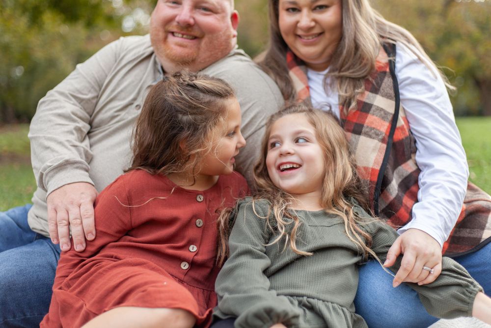 Candid family portrait outdoors showing joyful laughter and genuine connection during autumn photoshoot.