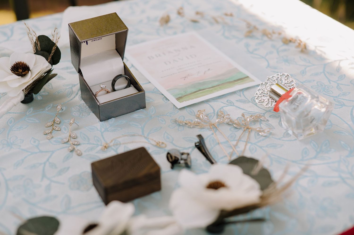 flat lay detail image of rings, invitations, perfume, and jewelry