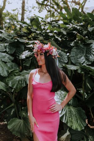Pink dress graduation portraits against large tropical leaves in garden setting.