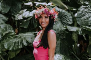 Tropical garden graduation photos with pink floral crown and dress.