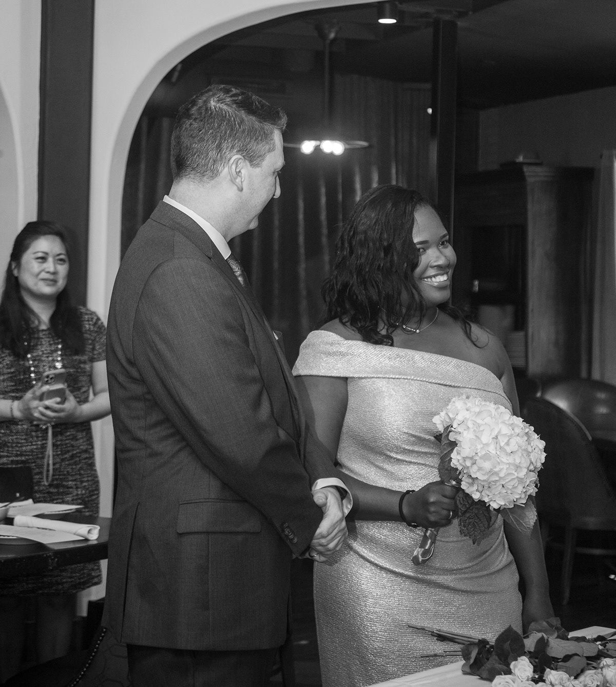 Wedding reception dance floor with couples dancing in formal attire and dim lighting.