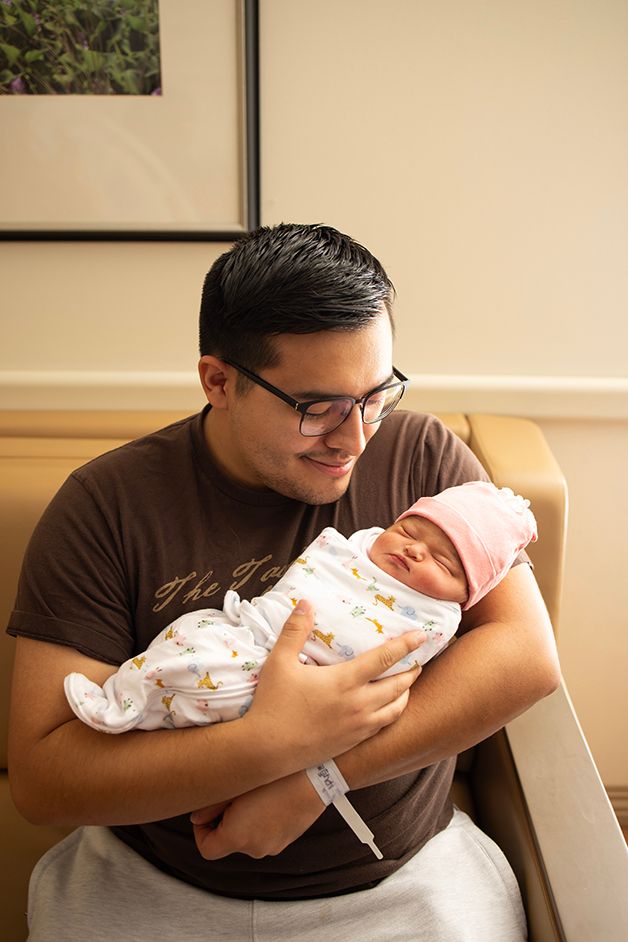 New dad holding his new baby girl.  Light from the window is cascading in from the side.