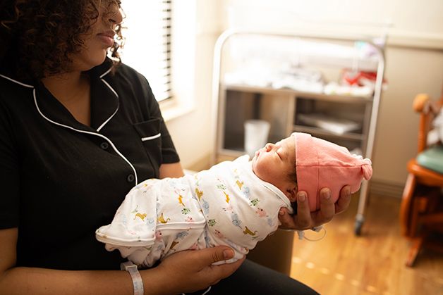 New mom holding newborn baby girl out infront of her.