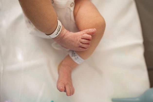Newborn wrinkly toes, baby girl is laying in the hospital bassinet.