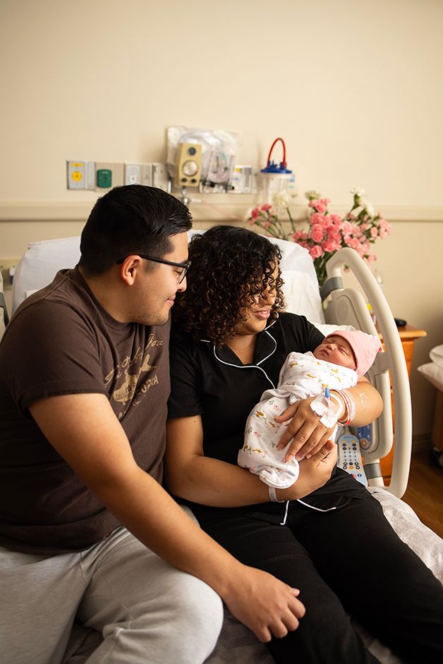 New parents looking down at their newborn baby girl smiling.