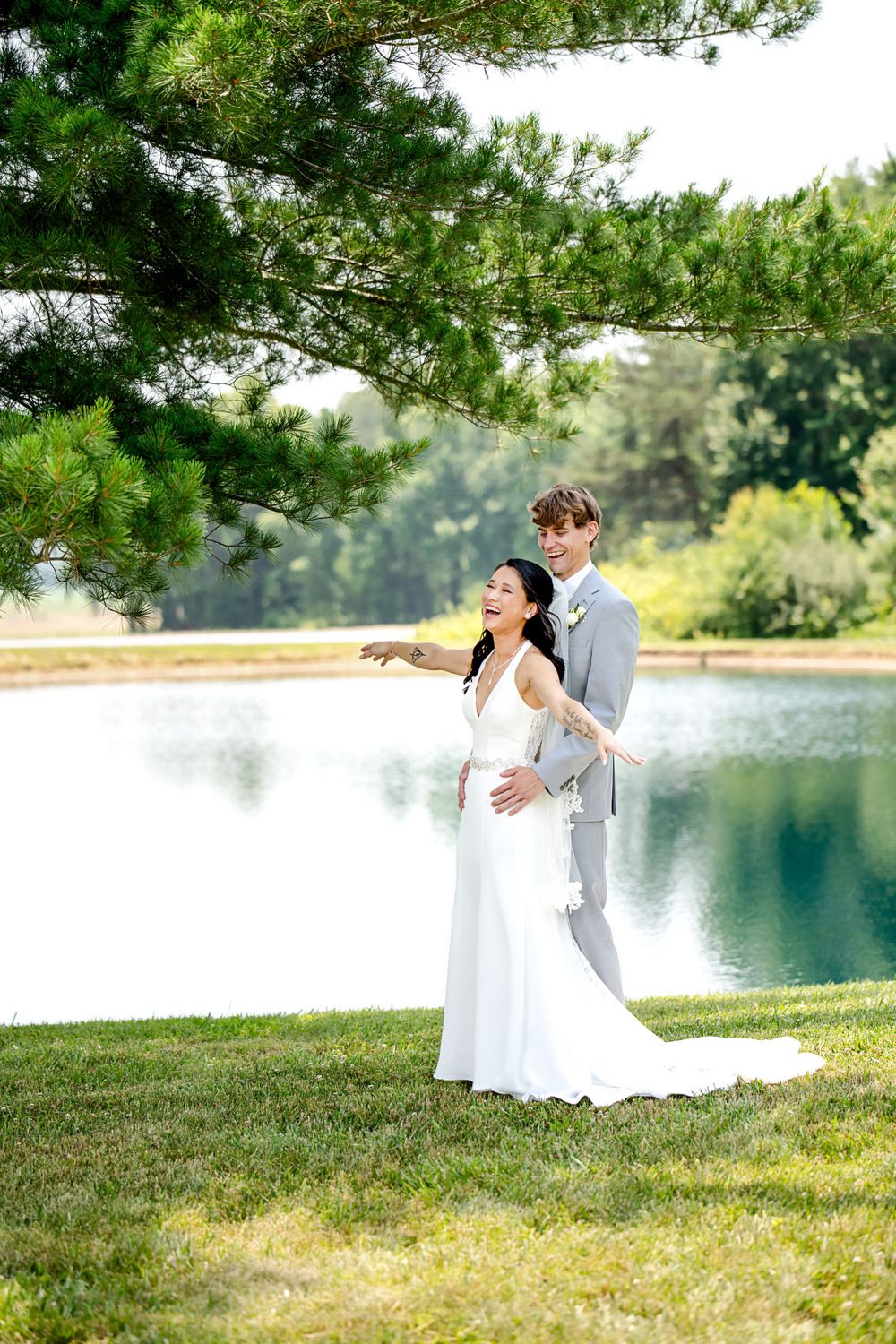 Wedding couple shares romantic moment by serene lakeside with pine trees in background.