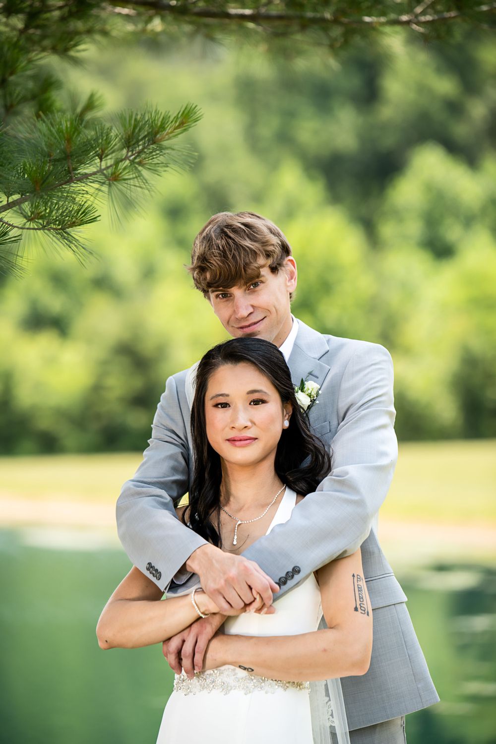 Romantic outdoor wedding photography session featuring white dress and grey suit in a natural setting.
