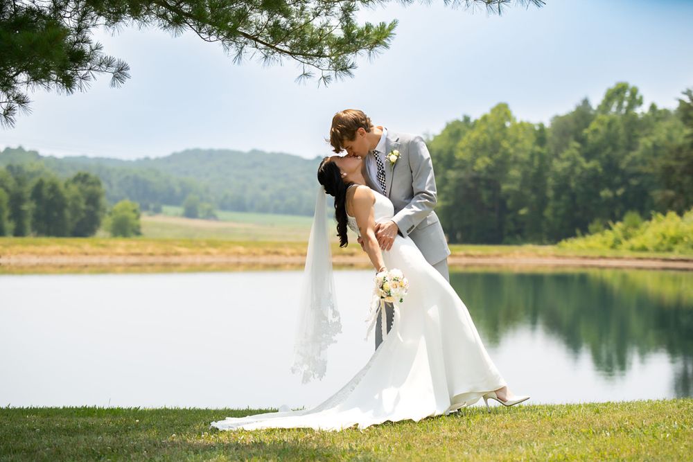 Romantic wedding couple posing for lakeside portrait with pine trees and mountains in background.