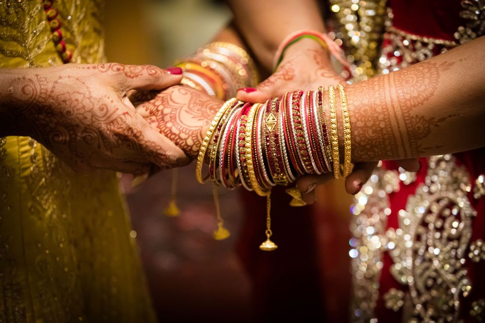 Close-up of hands adorned with traditional Indian wedding jewelry and bangles.