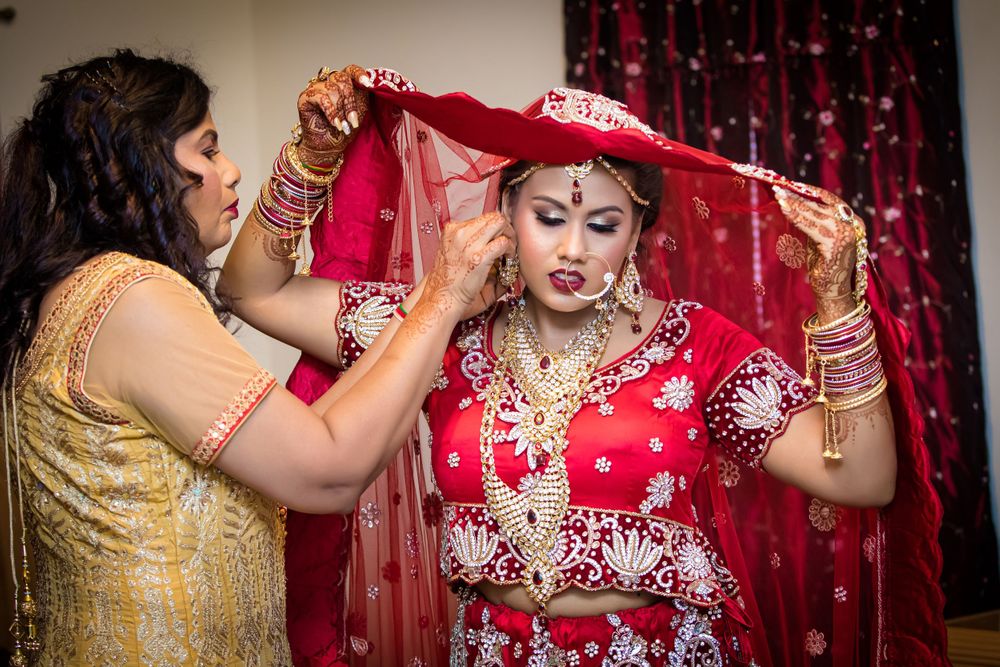 Traditional Indian bridal attire featuring intricate embroidery and jewelry against a red backdrop.