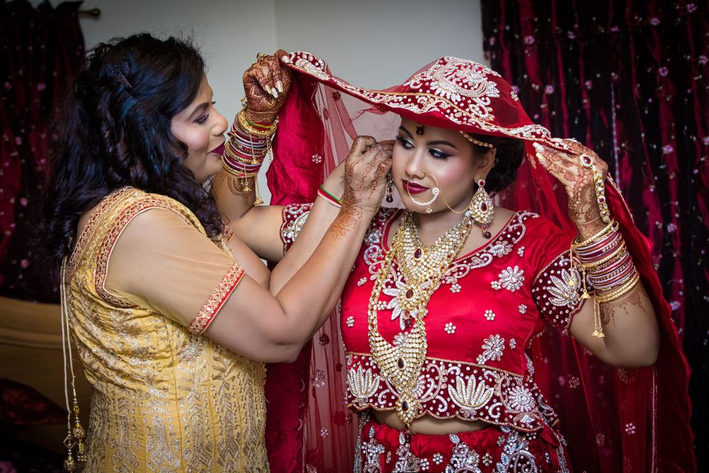 Close-up details of ornate Indian bridal jewelry and red embroidered fabric.