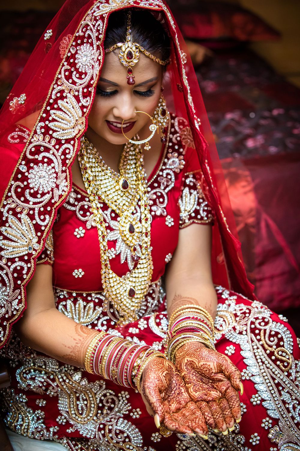 Elegant Indian bridal details showing mehndi, bangles, and embroidered red attire.