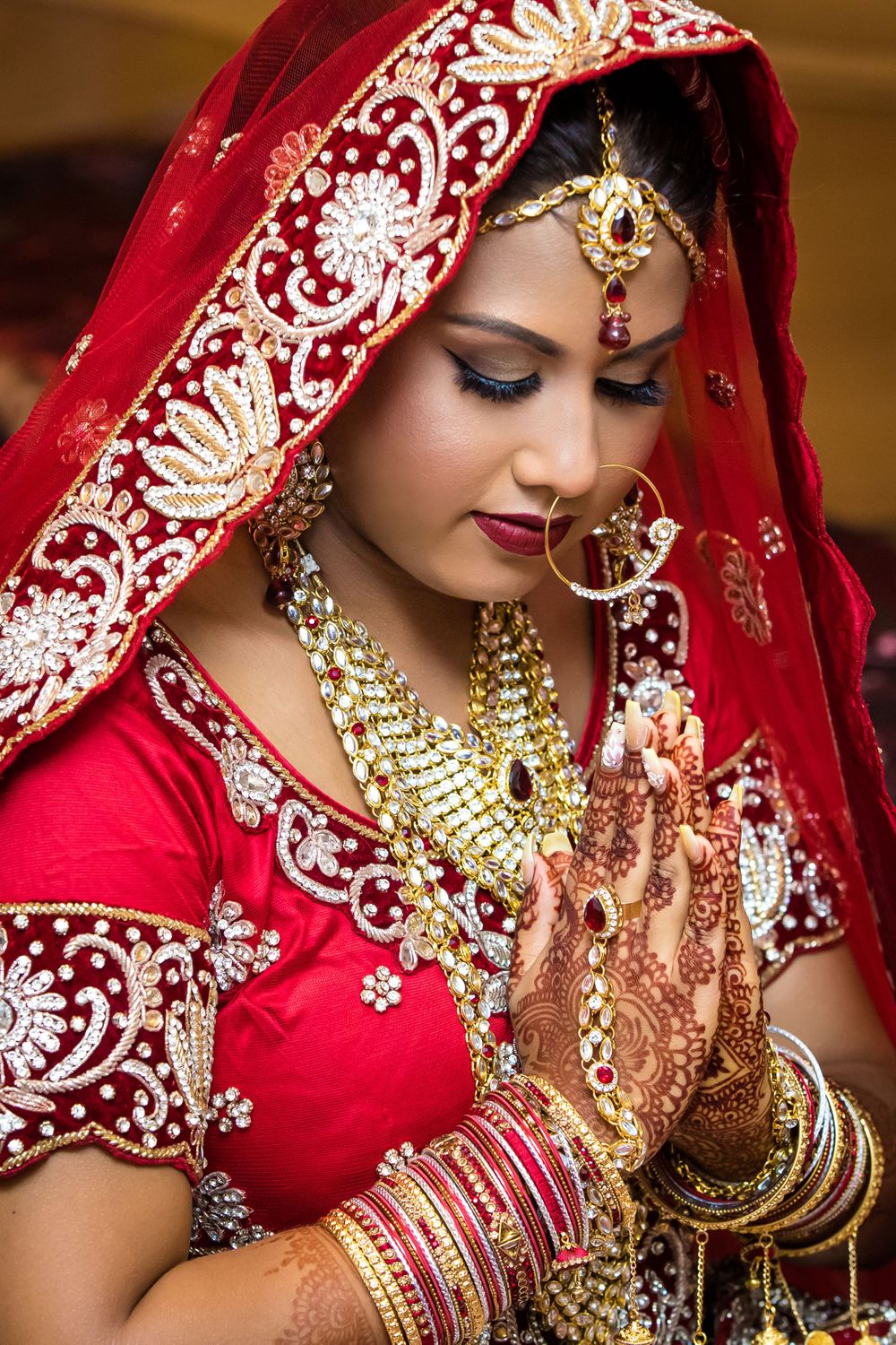 Traditional Indian bridal portrait with gold jewelry and red embroidered dress.
