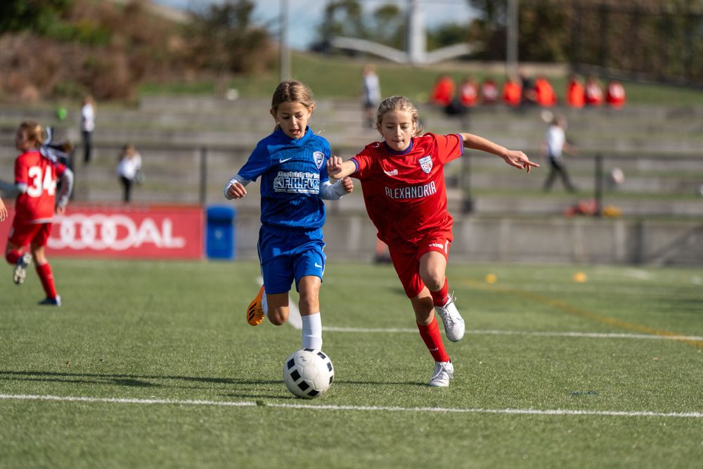 Two soccer players battle for control of the ball during an intense match.