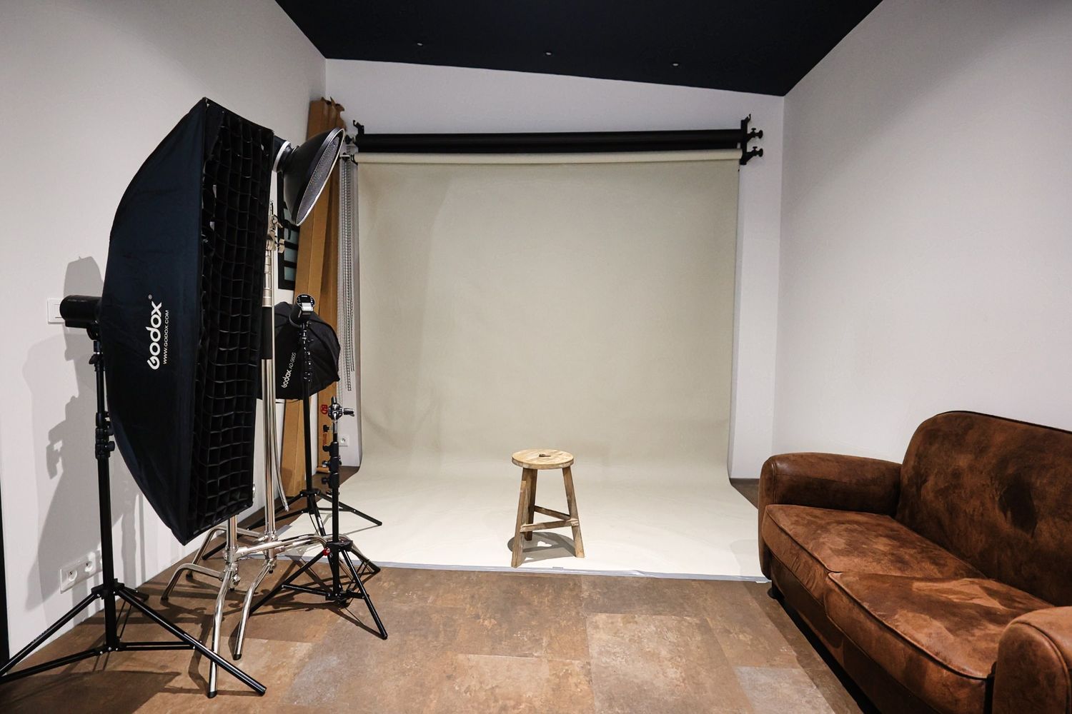 Empty photography studio interior with lighting equipment and brown leather couch.
