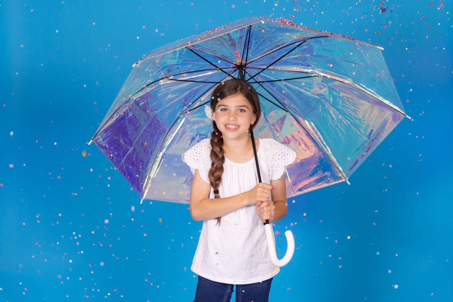 child holding irridescent umbrella on savage blue jay backdrop with confetti in studio in clayton new jersey Gloucester