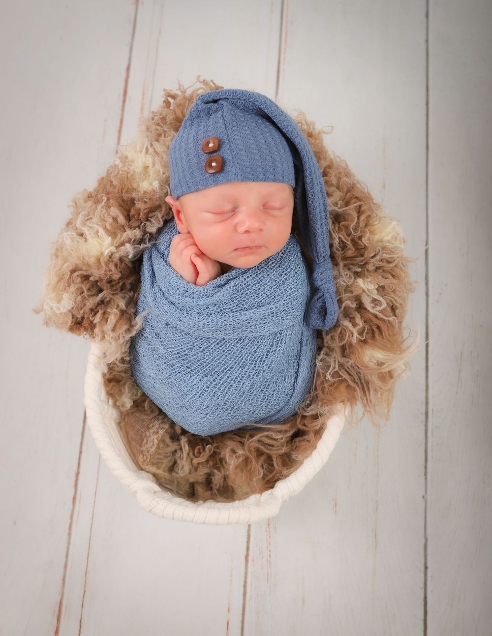 Newborn Photo Shoot with baby fast asleep , wearing a blue sleeping hat and wrapped in a beautiful blue cloth. Solihull Newborn Photographer