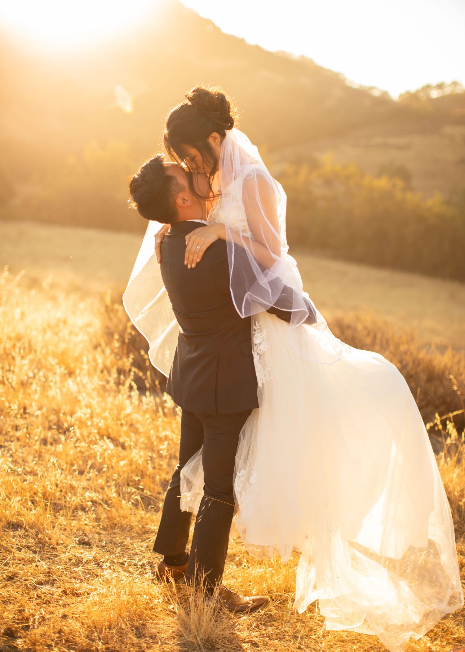Newlyweds share a romantic moment in a golden wheat field at sunset during their wedding photoshoot.