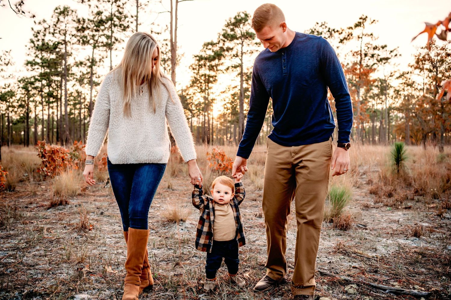 Family walking together through autumn forest during golden sunset.