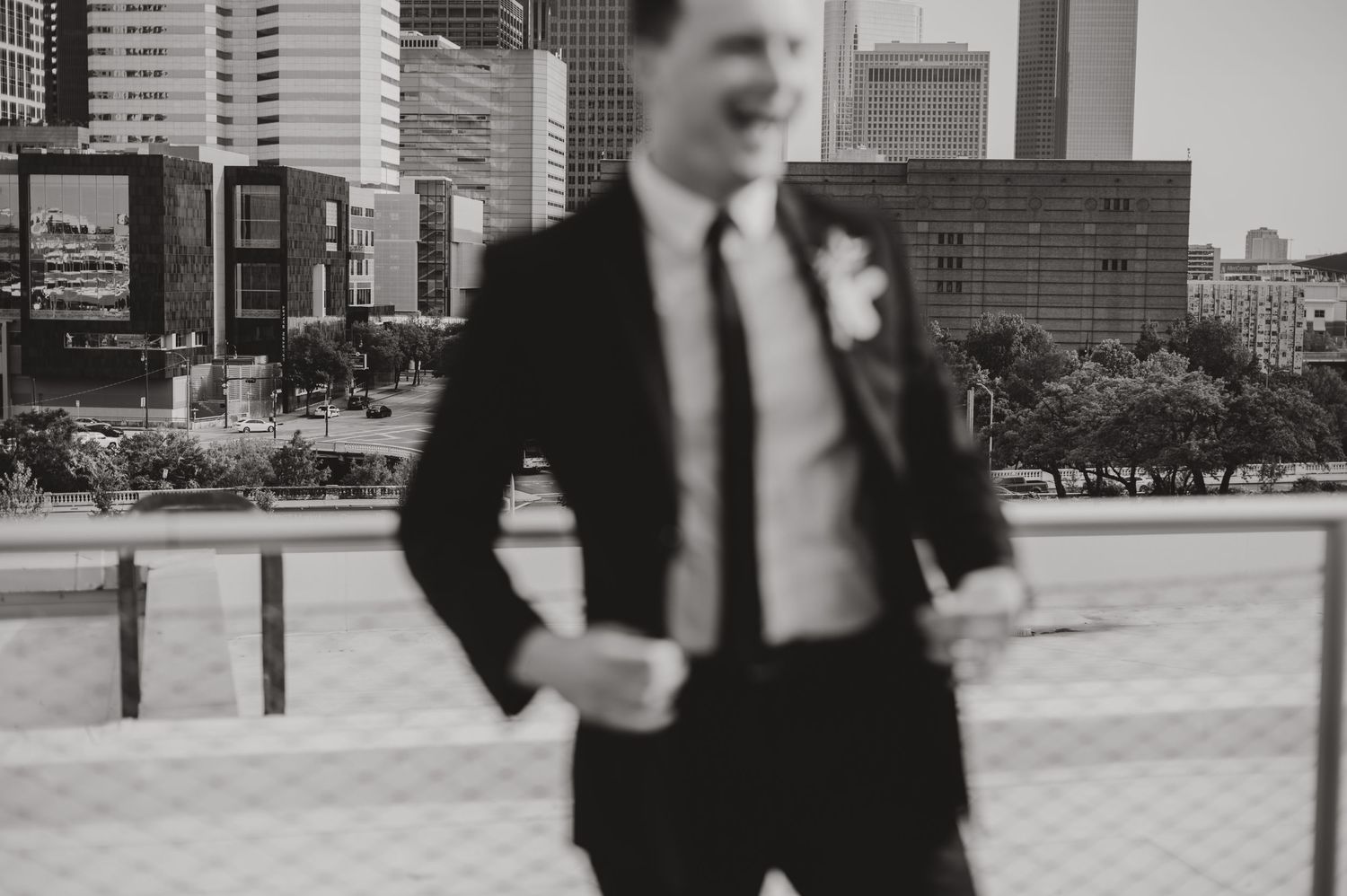 Black and white portrait of a groom in a sleek suit against an urban backdrop.