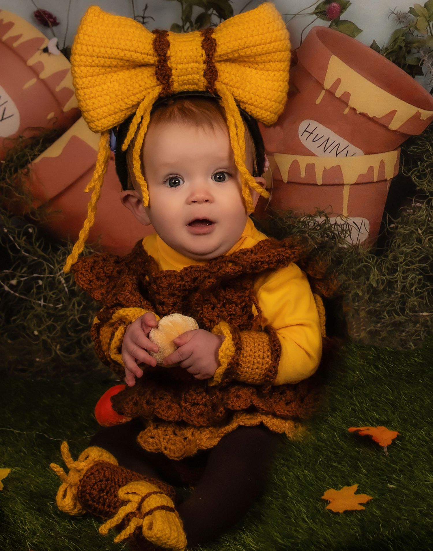 Yellow bow and honey-themed costume against autumn decorations and honey pots.
