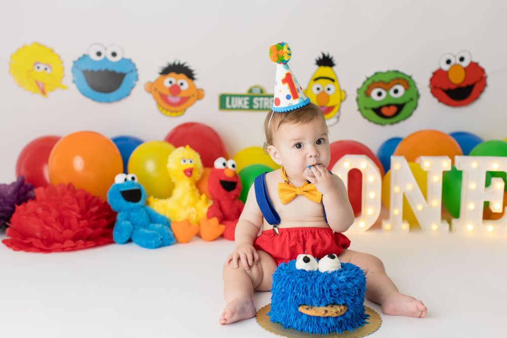 Birthday party setup with Sesame Street decorations and blue monster smash cake.
