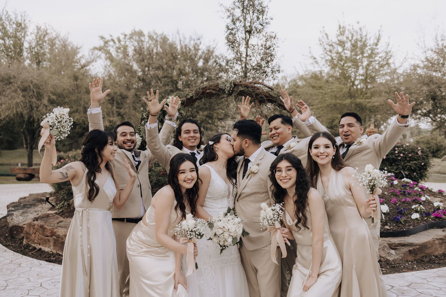 Wedding party celebrates joyfully holding bouquets in coordinated beige and white attire.