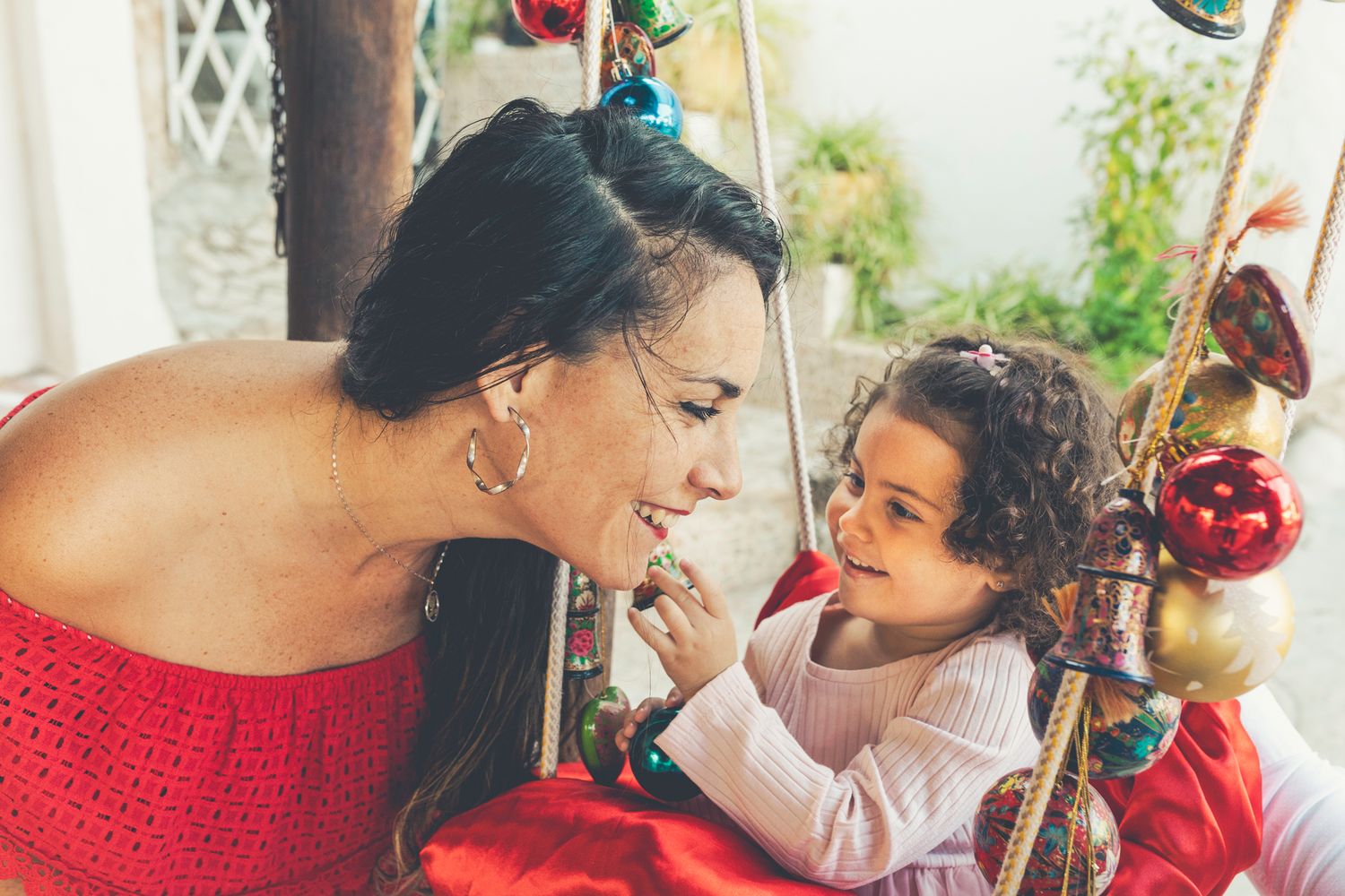 A candid moment shared between Corin and Lara while Lara is sitting on her swing, playing with the Christmas balls.