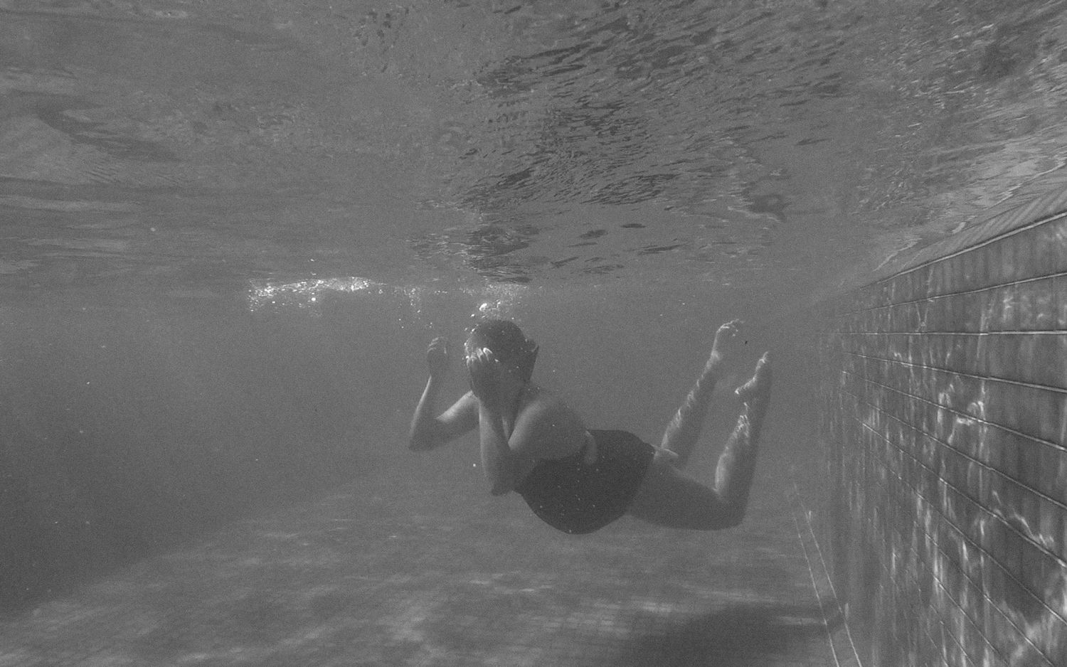 pregnant woman in black one piece swimming in a pool in black and white