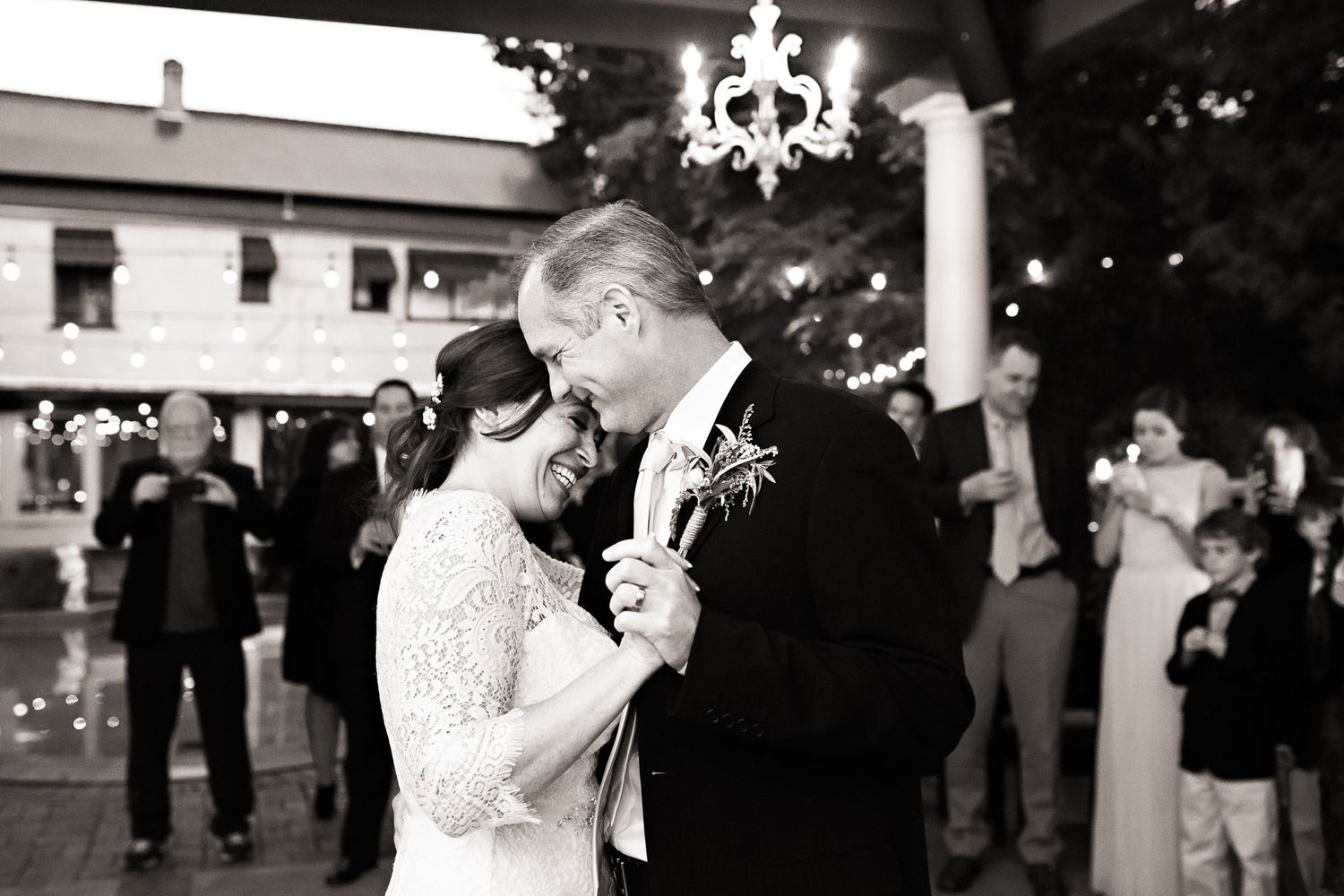 Black and white photo of couple sharing first dance at outdoor wedding reception.