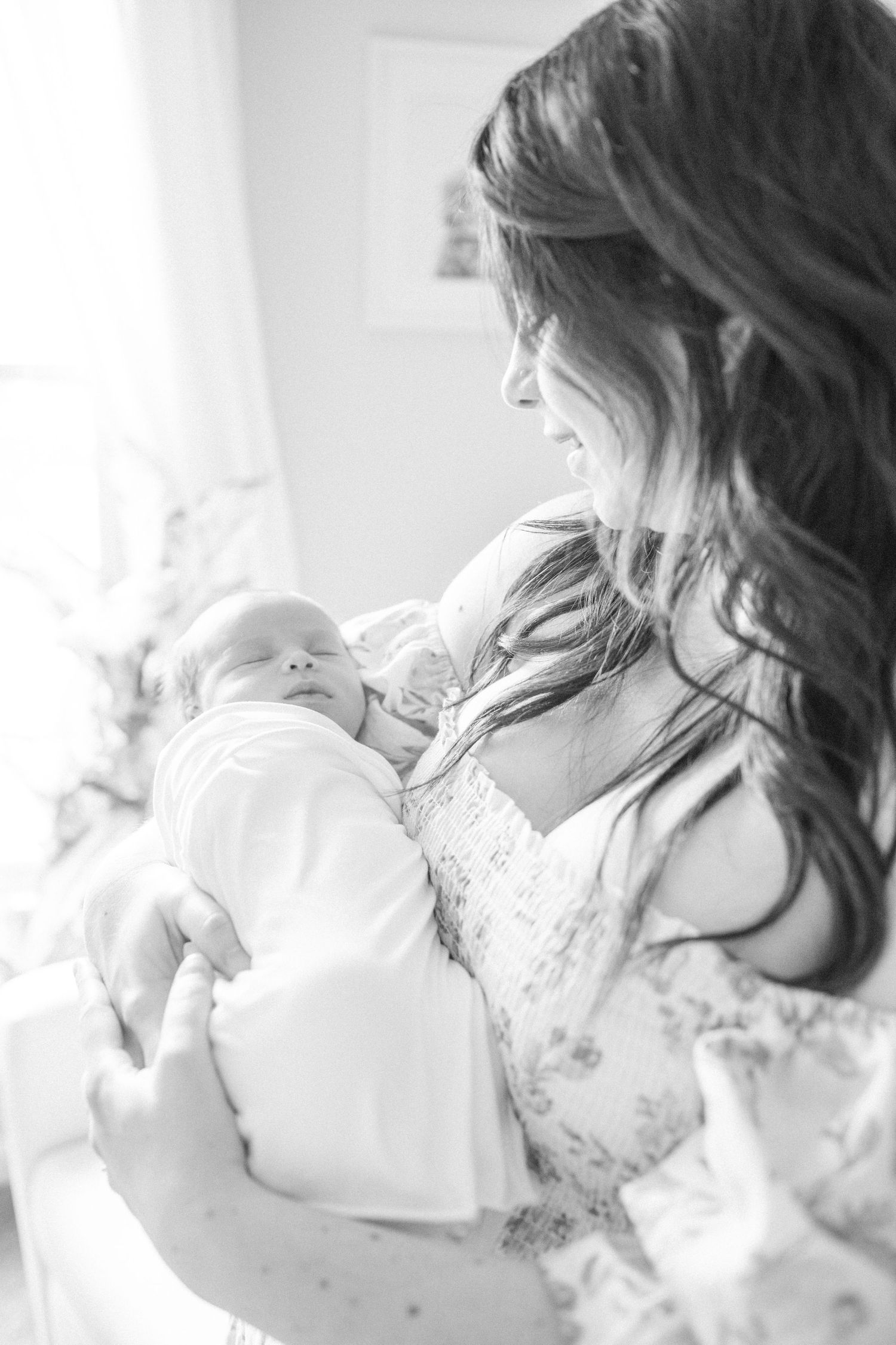 black and white image of mom holding baby boy swaddled in her arms