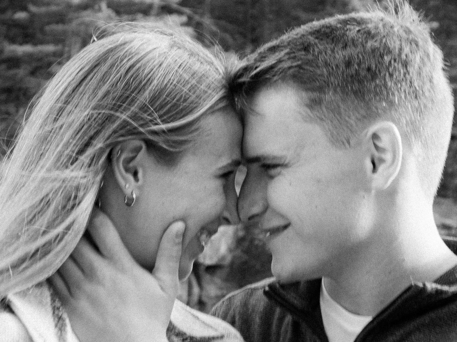 A romantic black and white close-up of a couple sharing an intimate moment with their foreheads touching.