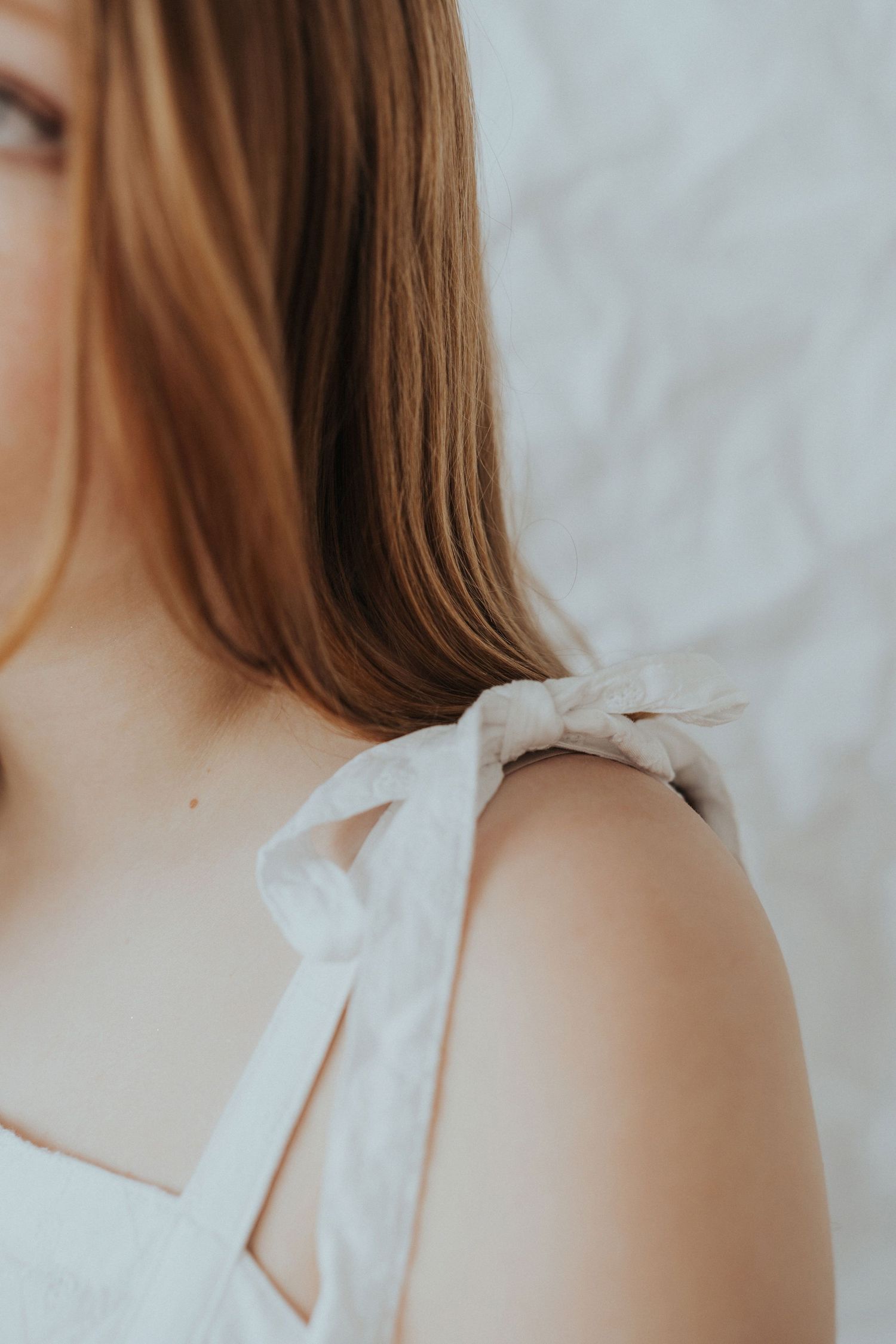 A redhead girl stands against a white paper backdrop