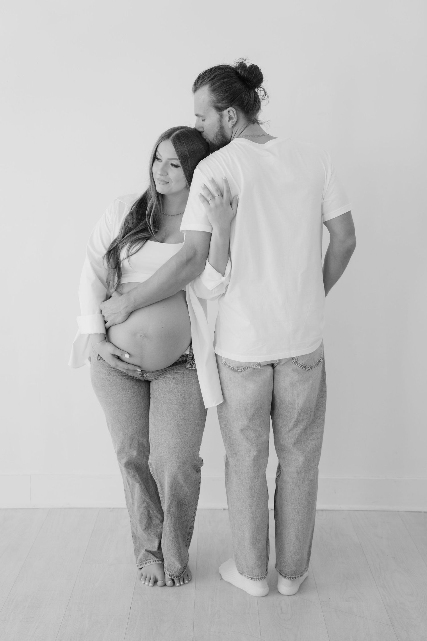 maternity photography session, husband embracing wife in a studio black and white located in dallas texas