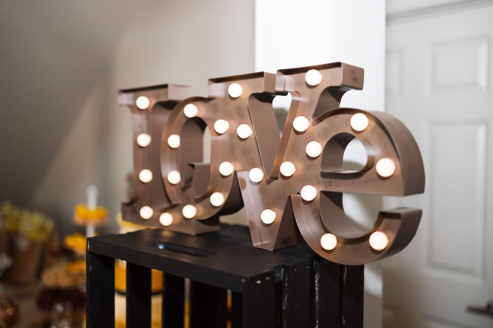 A decorative 'love' sign with illuminated marquee bulbs sits on a dark surface.