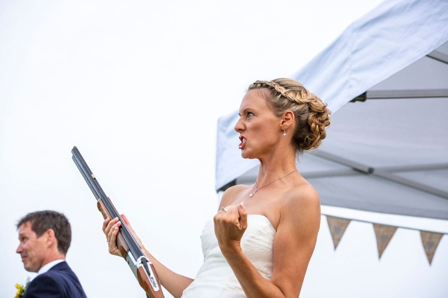 Wedding party members playfully aiming clay shooting rifles upward.