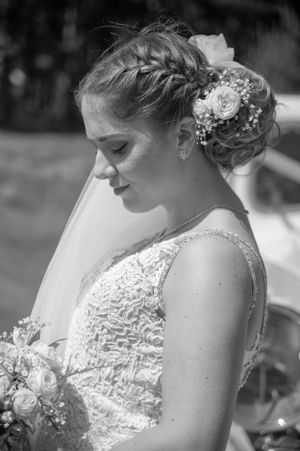 Bride with intricate braided updo and floral hair accessories in black and white portrait.