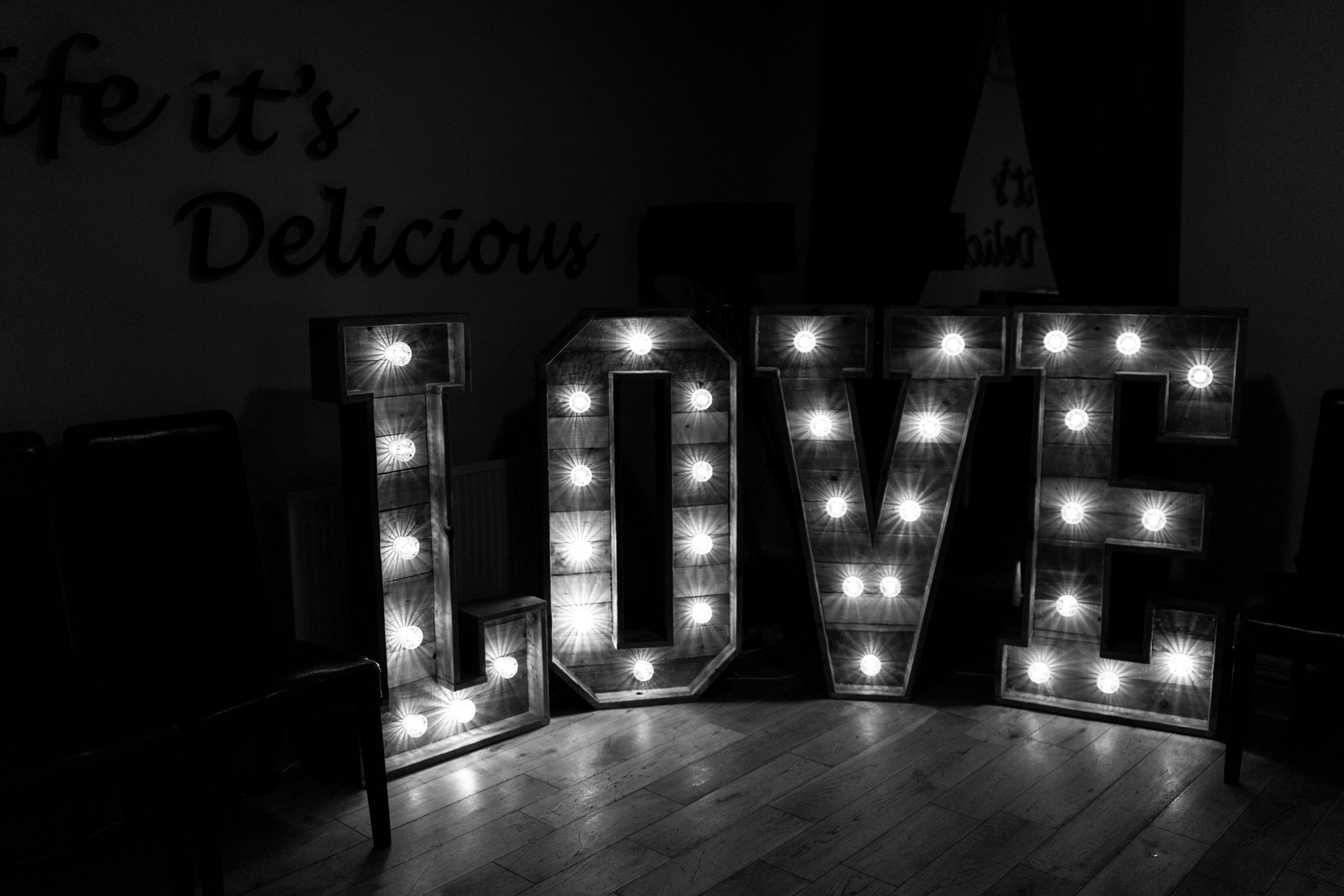 Black and white illuminated LOVE sign with marquee lights against dark background.